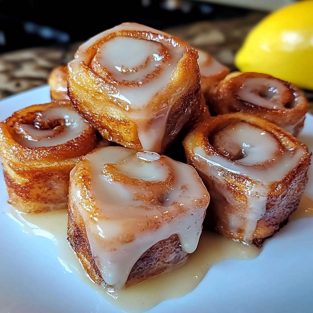 Plate of cinnamon roll French toast bites topped with cream cheese glaze and sprinkled with cinnamon sugar.