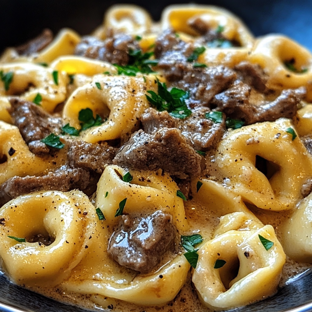 Bowl of Philly Cheesesteak Tortellini featuring tender steak, colorful bell peppers, and creamy cheese sauce.